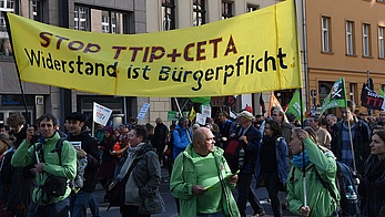 Menschen tragen auf einer Demo ein Banner mit der Aufschrift: STOP TTIP und CETA. Widerstand ist Bürgerpflicht.