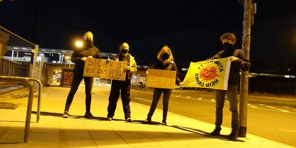 Vier Menschen mit Anti-Atom-Fahne, im Hintergrund Castor-Durchfahrt