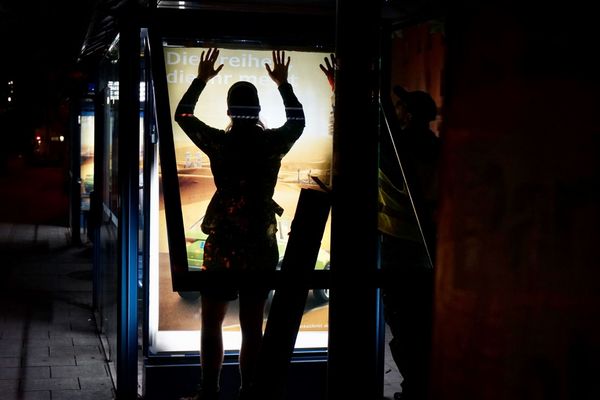 Ein Aktivist tauscht eine Werbung gegen ein Adbustignplakat aus im Dunkeln