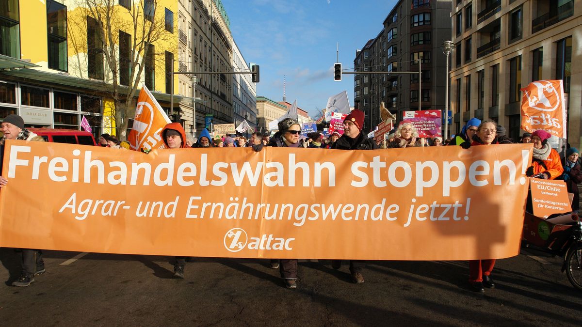 Aktivisti tragen oranges Banner "Freihandelswahn stoppen! Agrar- und Ernährungswende jetzt! attac und Logo