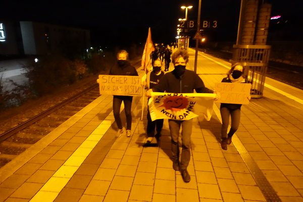 Aktivisten mit Anti-Atom-Fahne auf Bahnsteig bei Dunkelheit