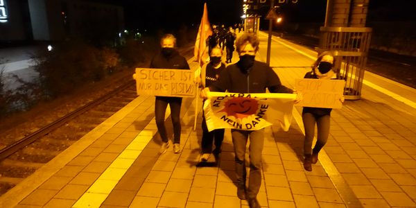 Aktivisten mit Anti-Atom-Fahne auf Bahnsteig bei Dunkelheit