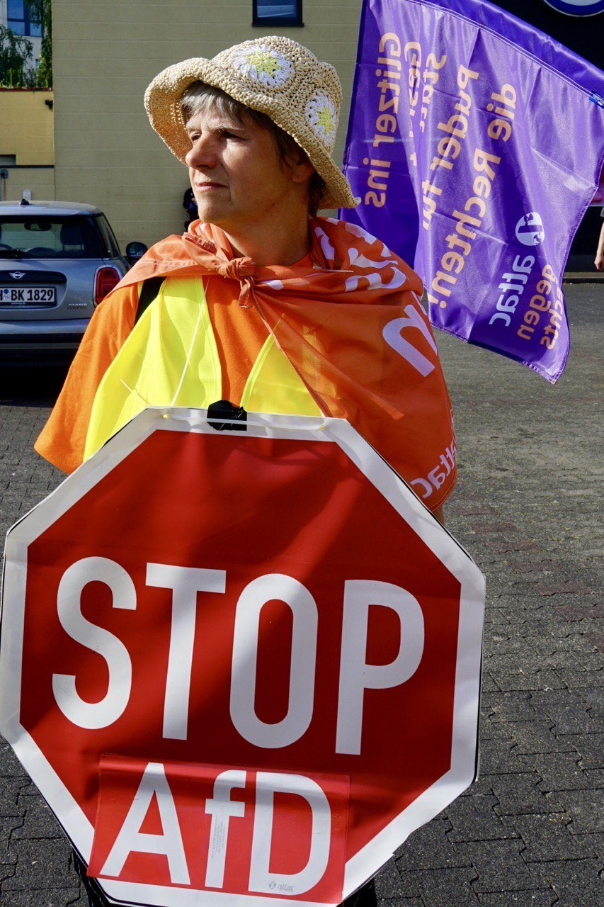 Attac-Aktivistin mit umgehängtem "Stop AfD"-Schild